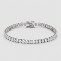 A silver tennis bracelet with a row of round-cut clear gemstones, displayed on a light gray background.