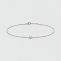 A delicate silver chain anklet with a small central oval charm, displayed on a clean light gray background.