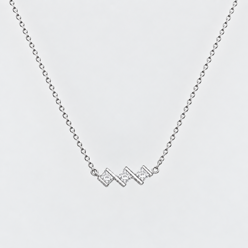 A silver chain necklace featuring a small zigzag pendant paved with clear stones, shown against a light gray background.