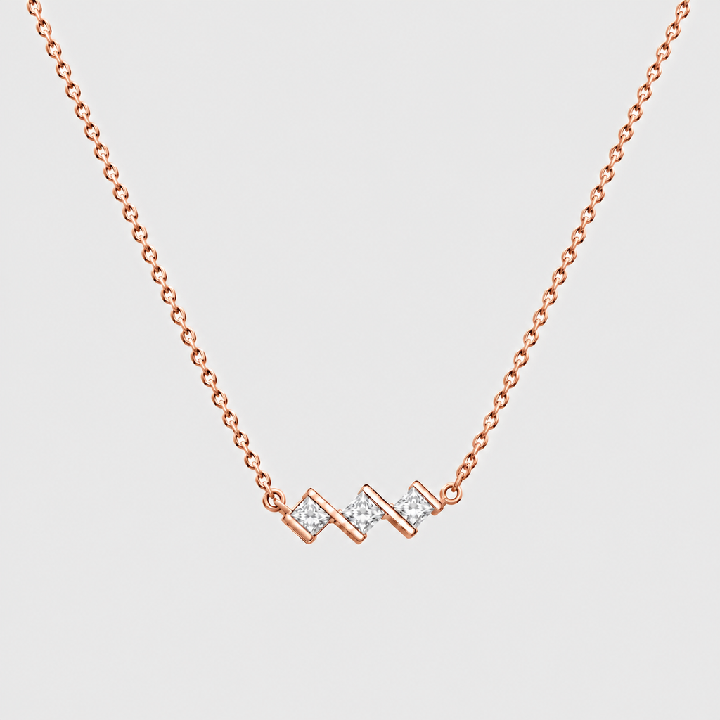 A delicate rose gold chain necklace featuring a modern zigzag pendant adorned with small clear pavé stones, set against a solid light gray background.