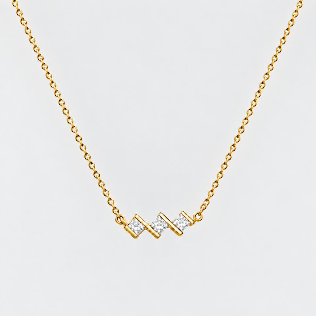 A gold chain necklace with a zigzag pendant featuring small clear stones, shown against a light gray background.
