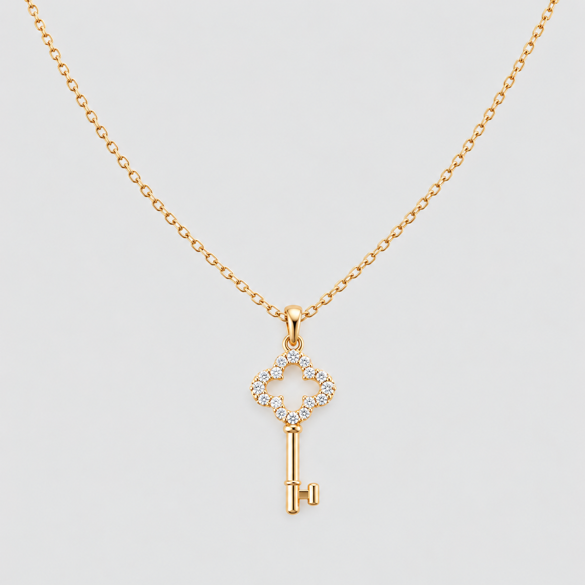 A gold key pendant necklace with a diamond-encrusted key head, displayed on a clean light gray background.