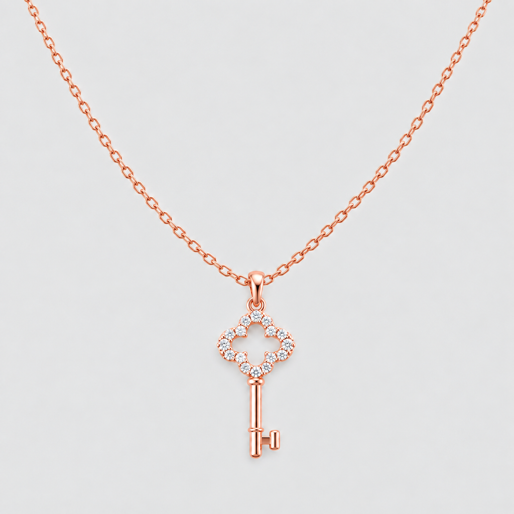 A rose gold key-shaped pendant necklace with a small diamond halo on the key bow, shown against a light gray background.