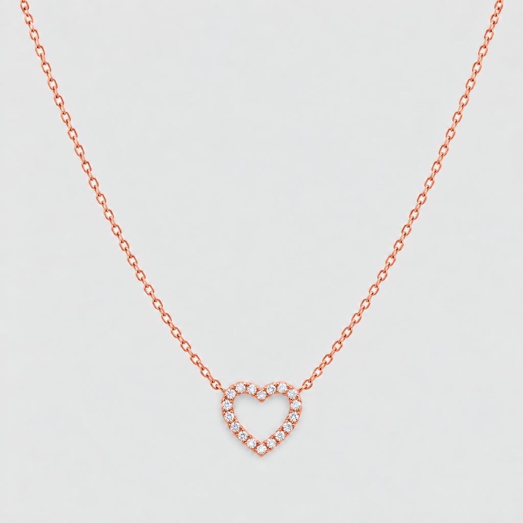 A delicate rose gold chain necklace featuring a heart-shaped pendant paved with small clear stones, displayed against a clean, light gray background.