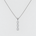 A silver chain necklace with a vertical pendant featuring four small clear gemstones in a prong setting, shown against a light gray background.