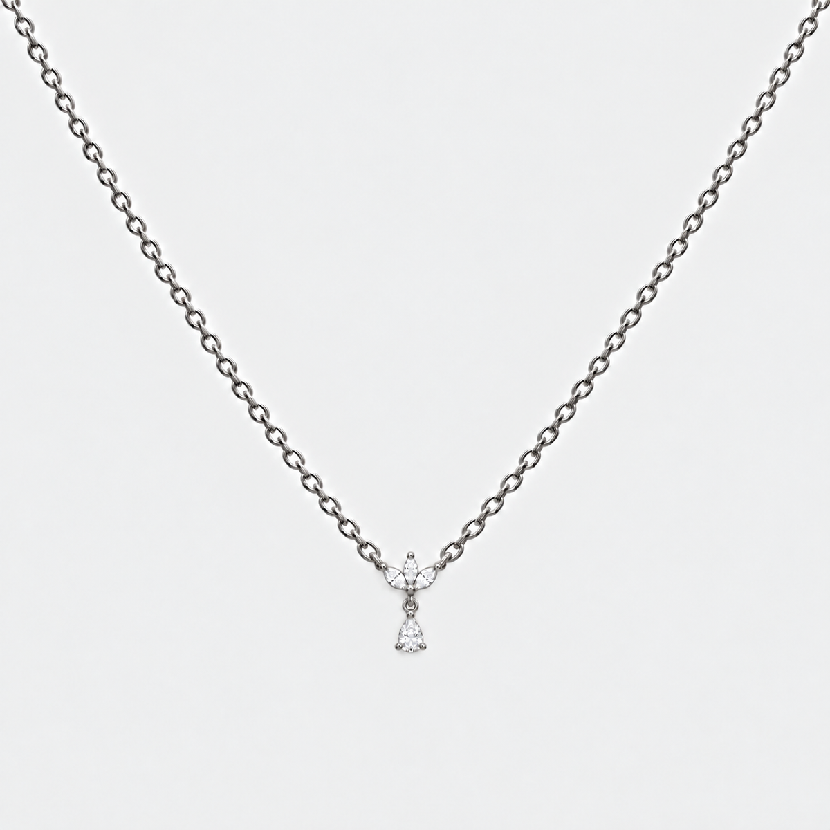 A delicate silver chain necklace with a small bow-shaped pendant set with clear gemstones, displayed against a light gray background.