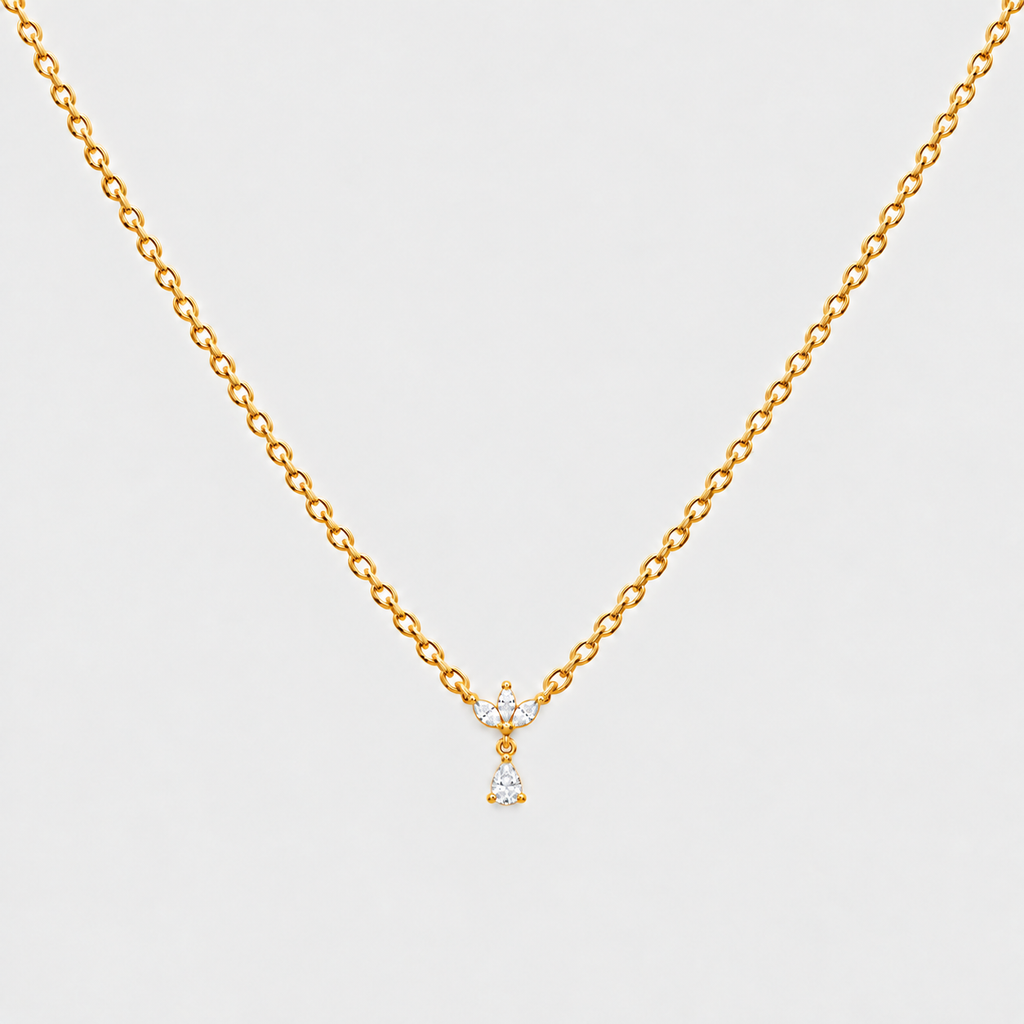 A delicate gold chain necklace with a small bow-shaped pendant set with clear gemstones and a dangling clear crystal, shown on a light gray background.