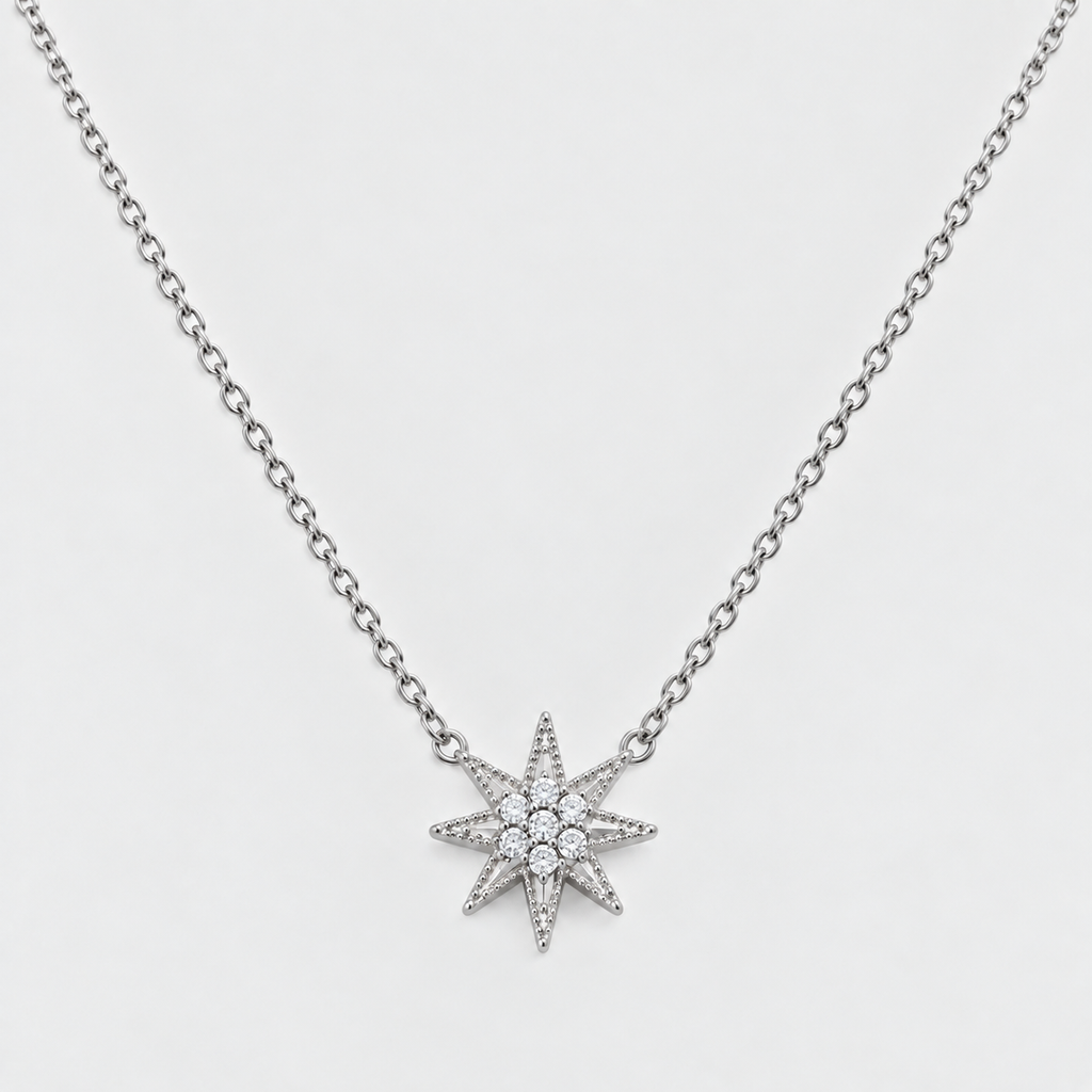 A silver-toned chain necklace featuring a multi-pointed starburst pendant paved with small clear stones, shown against a light gray background.