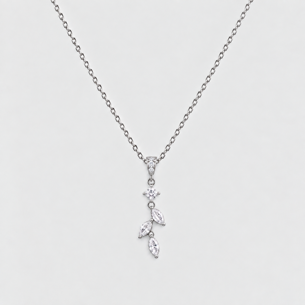 A delicate silver-toned necklace featuring a small floral and leaf pendant set with clear marquise and round-cut stones, displayed against a light gray background.