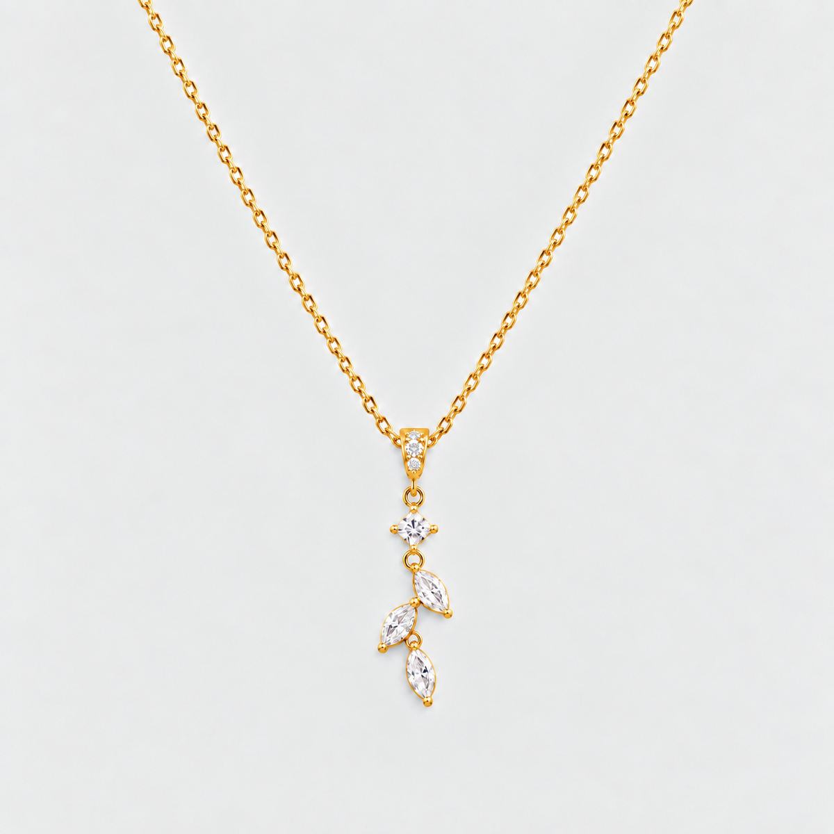 A gold chain necklace with a delicate pendant featuring a small star and three marquise-cut clear stones set in gold, displayed against a light gray background.
