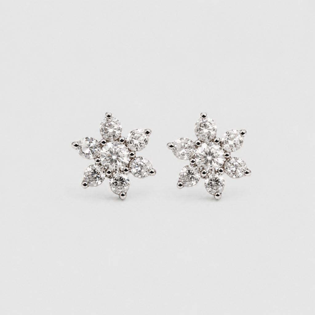 A pair of snowflake-shaped stud earrings made of silver metal and clear gemstones, set against a plain light gray background.