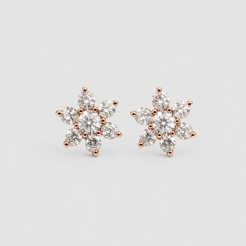 A pair of rose gold stud earrings featuring a six-petal flower design set with clear round and marquise-cut gemstones, displayed on a light gray background.
