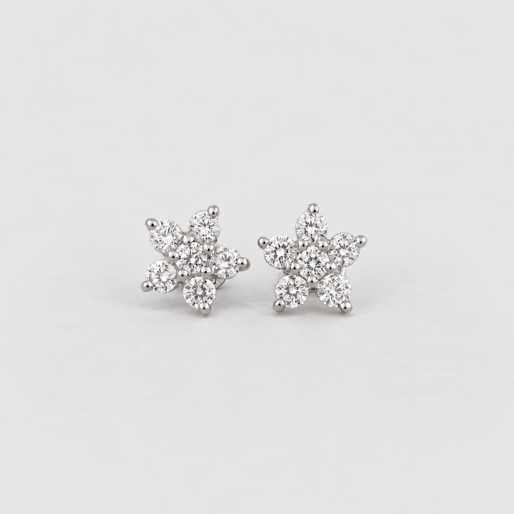 A pair of silver stud earrings shaped like snowflakes, set with small clear cubic zirconia stones, on a light gray background.