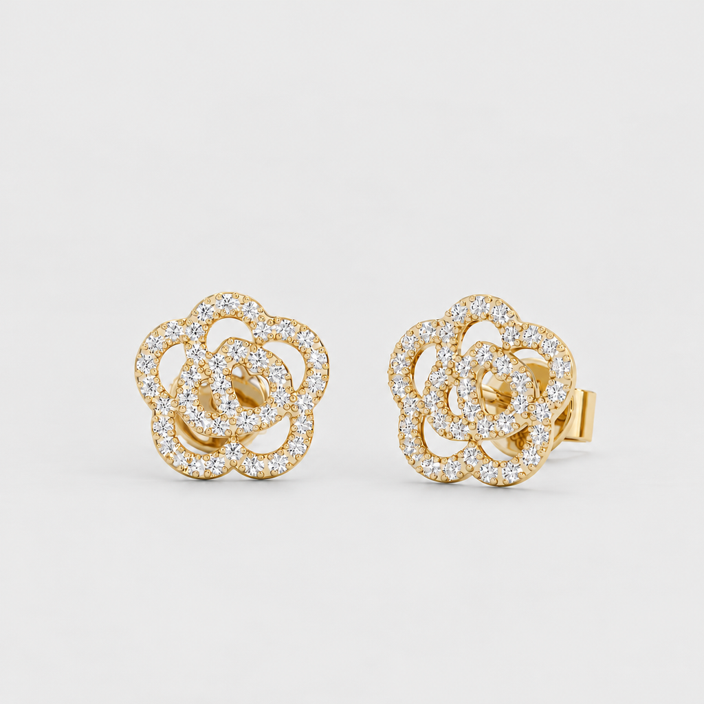 A pair of gold stud earrings featuring a multi-layered flower design paved with small clear stones, set against a light gray background.