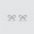 A pair of silver bow stud earrings paved with small clear gemstones, set against a clean light gray background.
