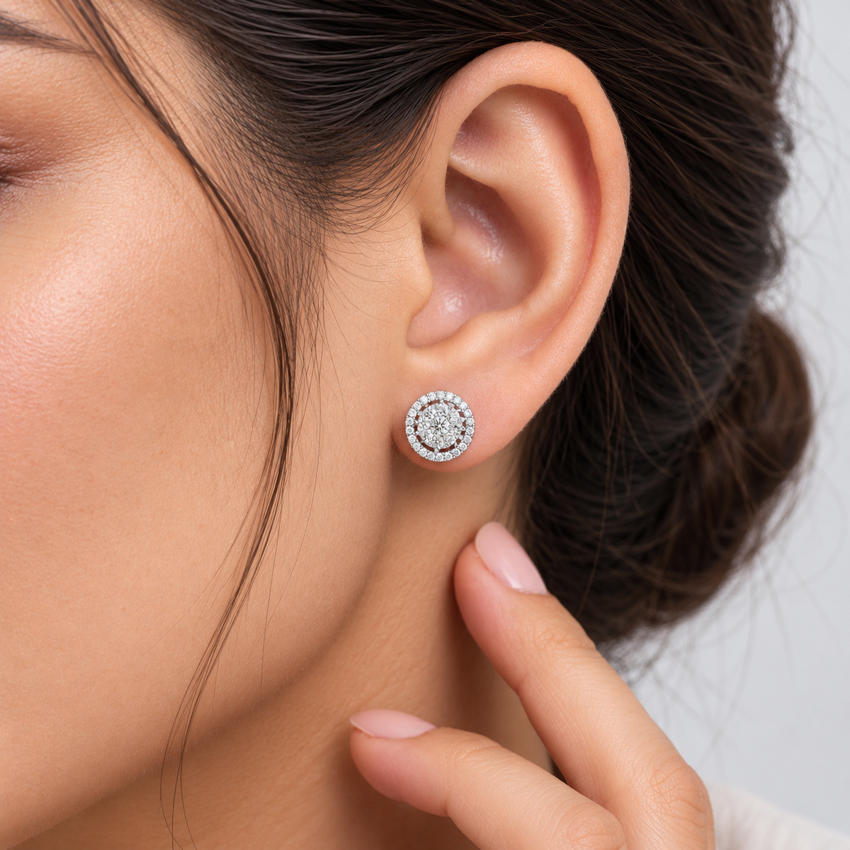 A close-up shot of a woman wearing a round cluster diamond stud earring