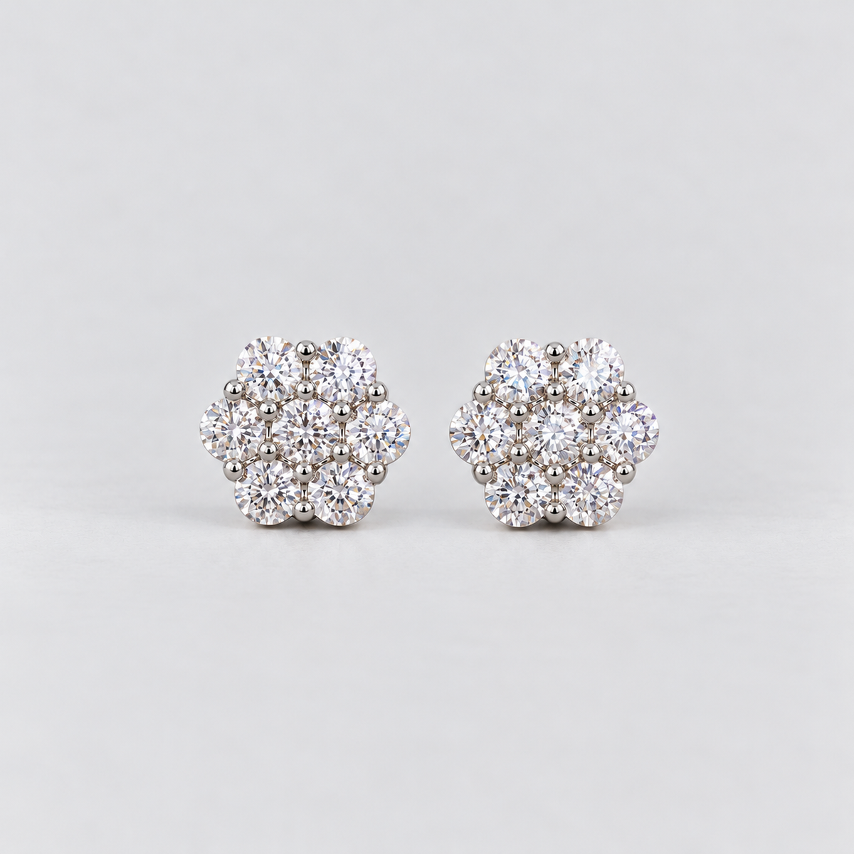 A pair of women's diamond cluster stud earrings in a hexagonal floral pattern in white gold metal.
