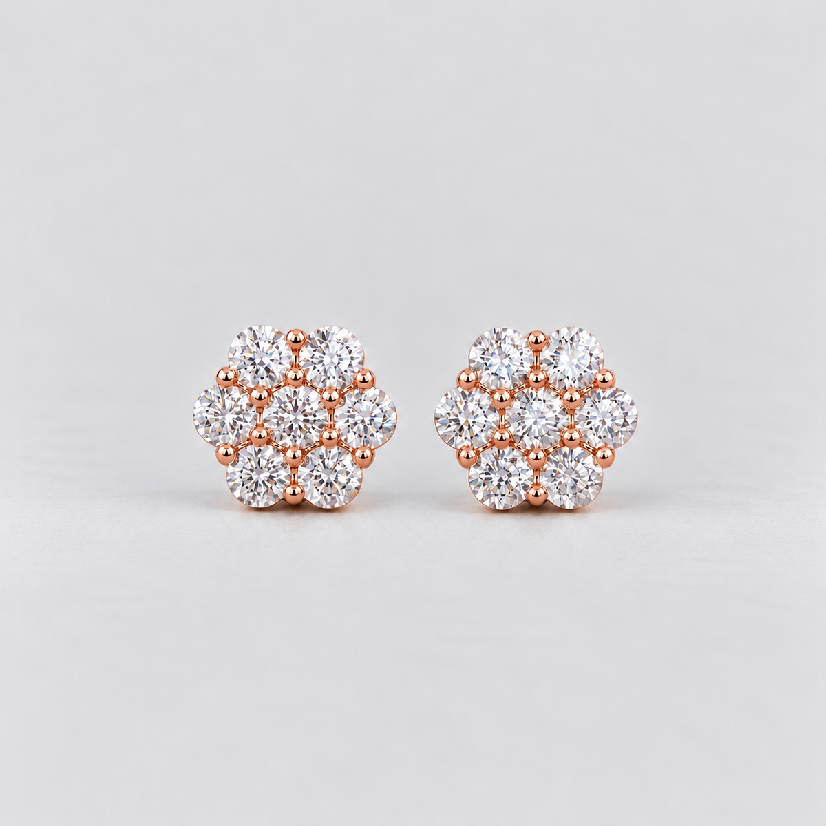 A pair of women's diamond cluster stud earrings in a hexagonal floral pattern in rose gold metal.