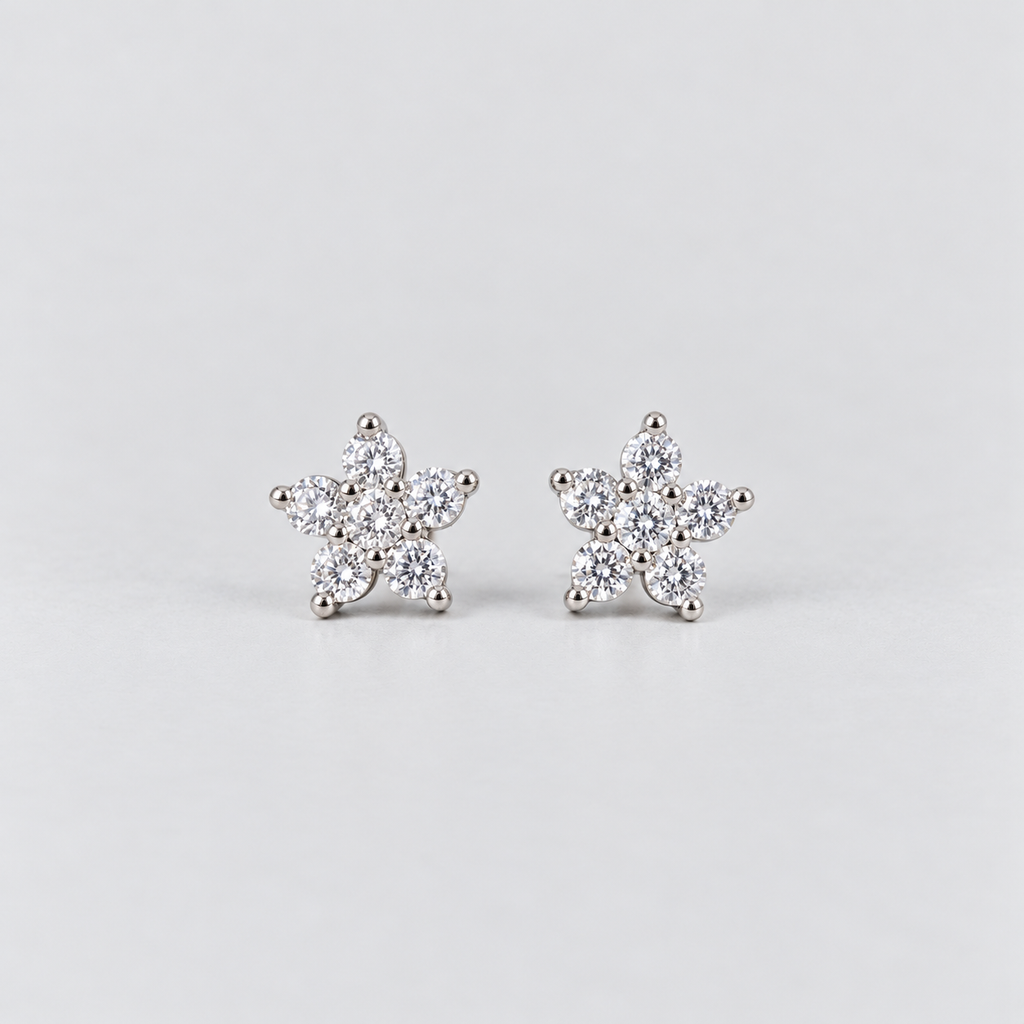 A pair of silver stud earrings shaped like snowflakes, each adorned with small clear round-cut gemstones, set against a plain light gray background.