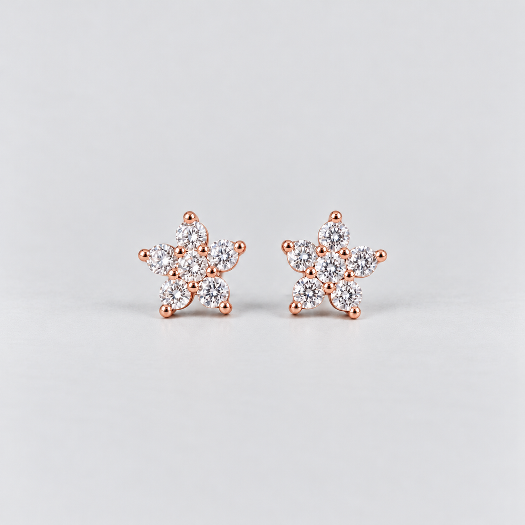 A pair of rose gold stud earrings with a snowflake or flower-like design set with clear gemstones, displayed on a light gray background.