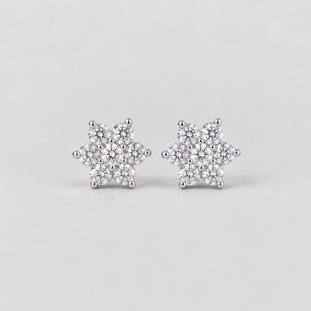 A pair of snowflake-shaped stud earrings made of silver metal and clear gemstones, set against a plain light gray background.