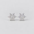A pair of snowflake-shaped stud earrings made of silver metal and clear gemstones, set against a plain light gray background.