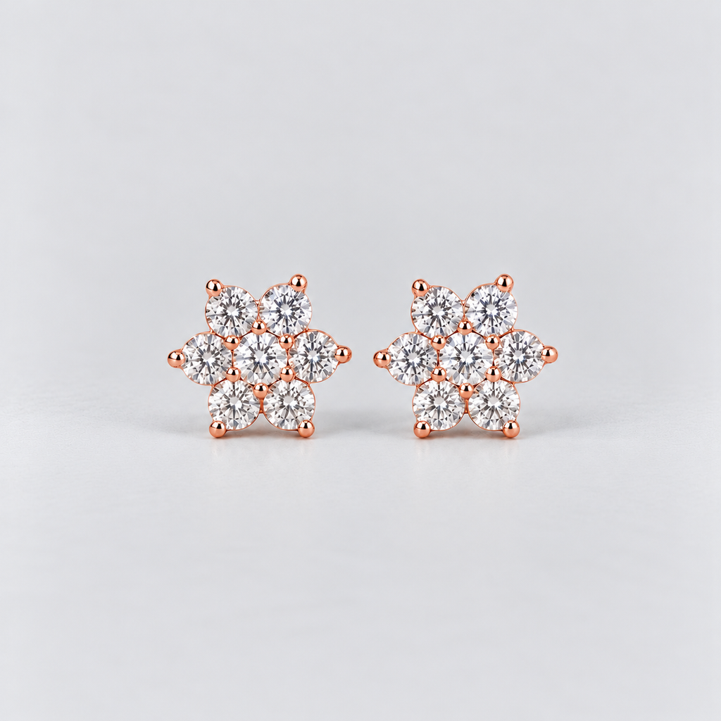 A pair of rose gold stud earrings featuring a snowflake-like cluster design set with clear round-cut gemstones, photographed on a light gray background.