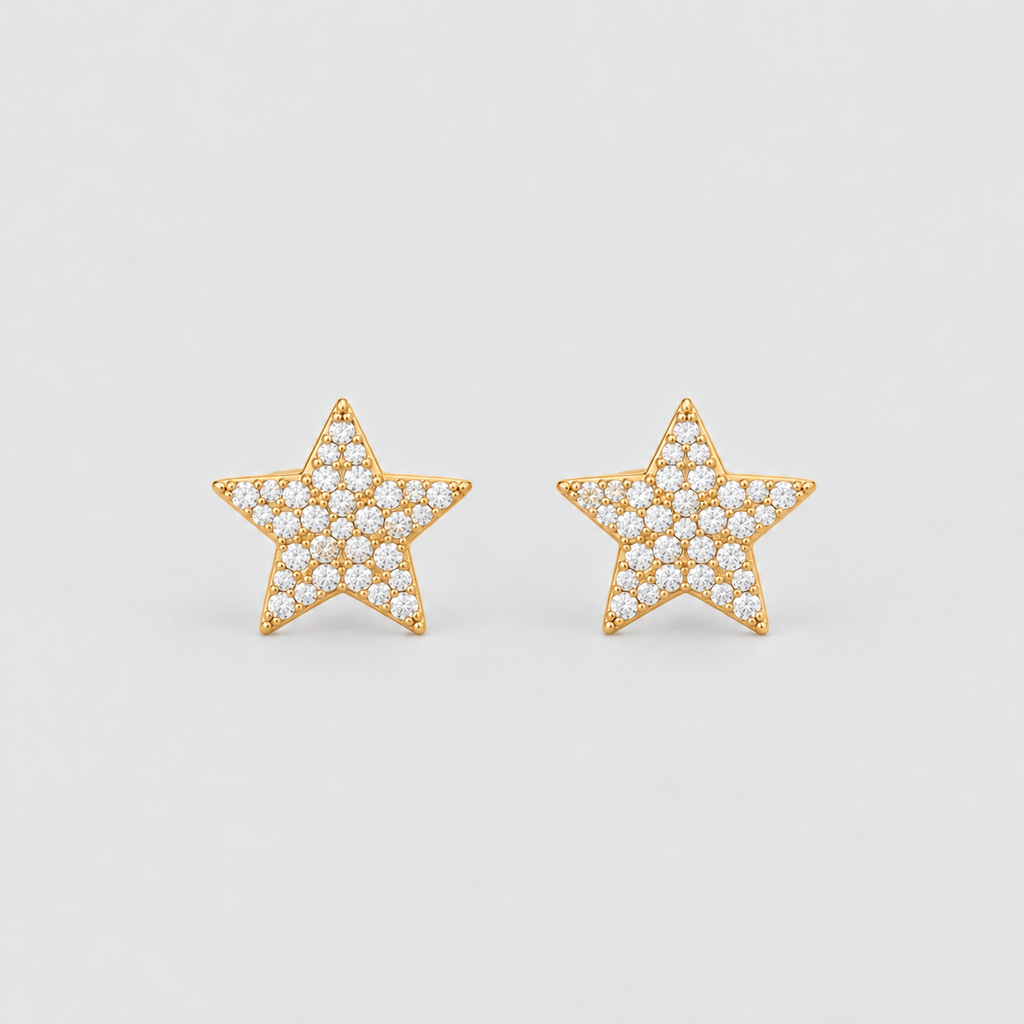 A pair of gold star-shaped stud earrings paved with small clear stones, set against a plain light gray background.