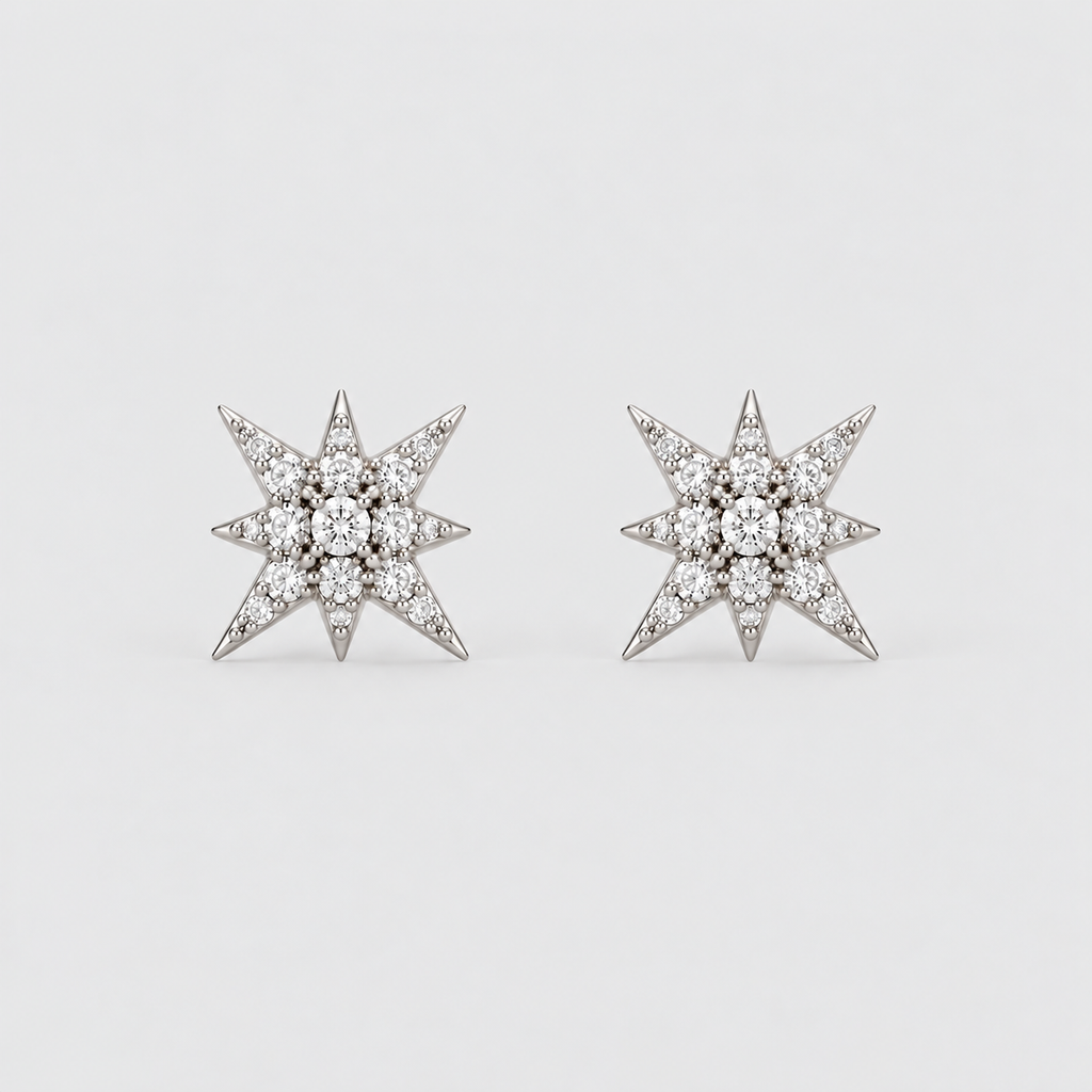A pair of star-shaped stud earrings set with clear gemstones in a silver-toned metal, displayed on a clean, light gray background.