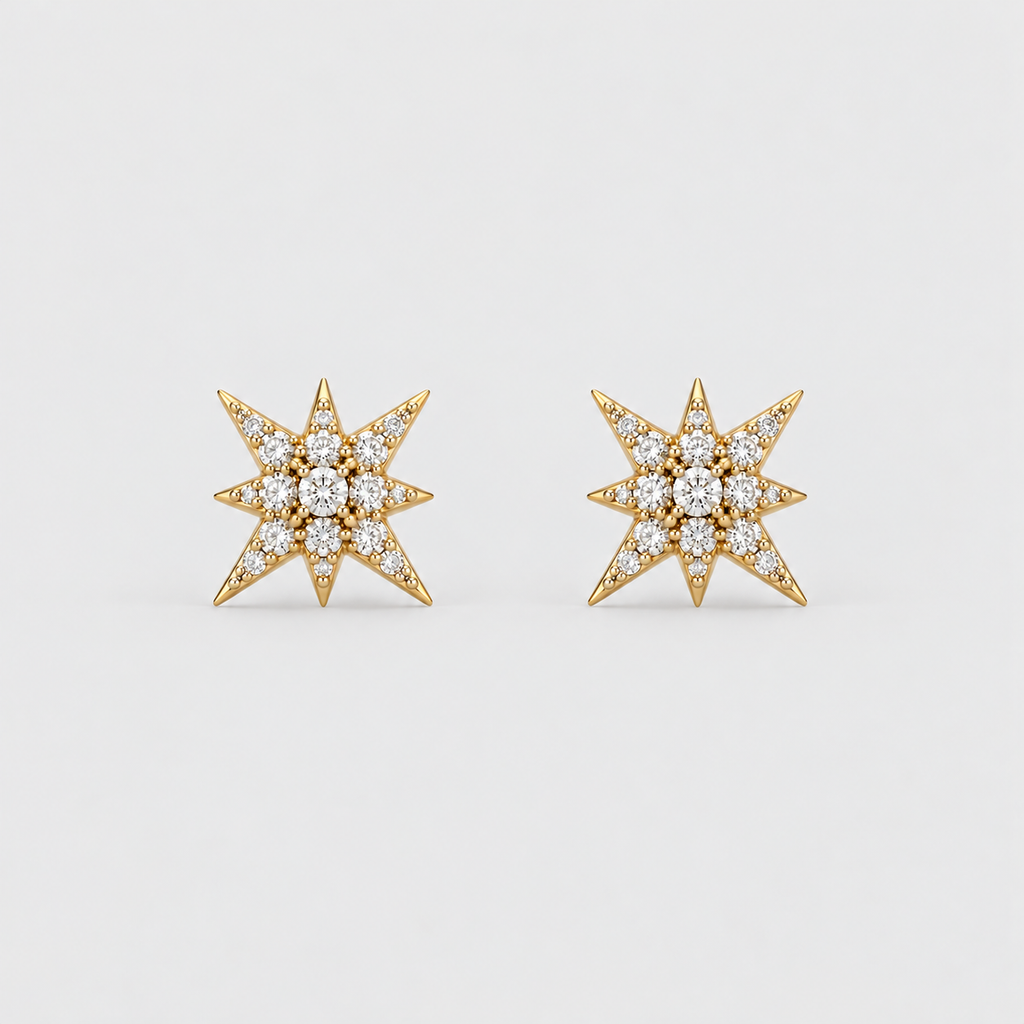 A pair of gold starburst stud earrings set with clear pavé gemstones, shown on a light gray background.