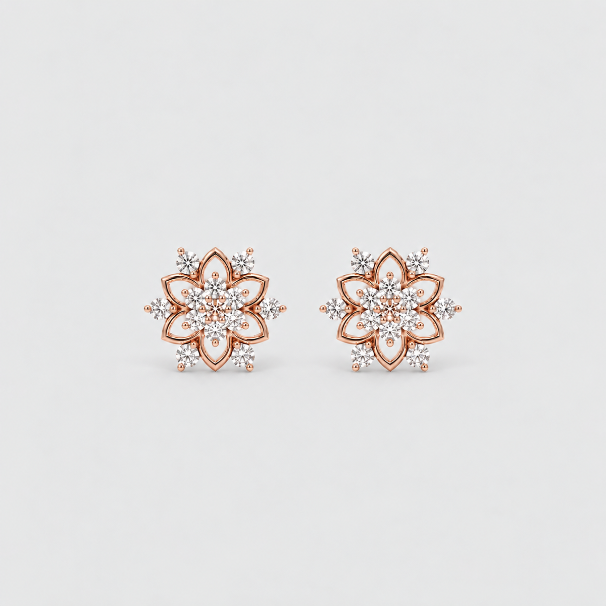 A pair of rose gold stud earrings with a floral mandala design, featuring clear pavé-set gemstones, shown on a light gray background.
