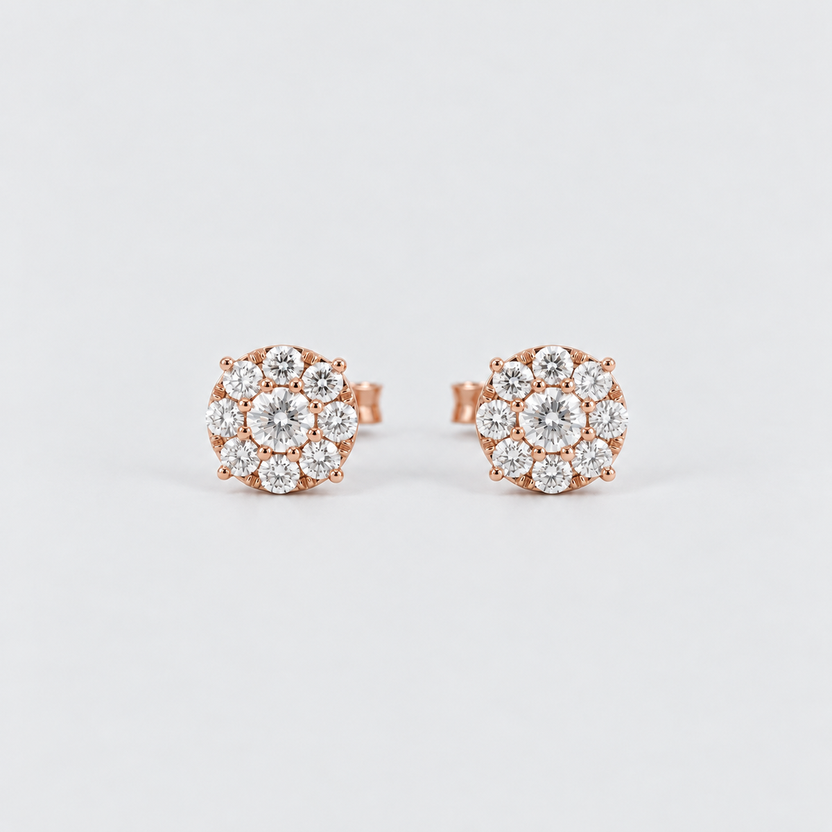 A pair of rose gold stud earrings with round-cut clear gemstones arranged in a flower-like cluster, photographed on a clean light gray background.