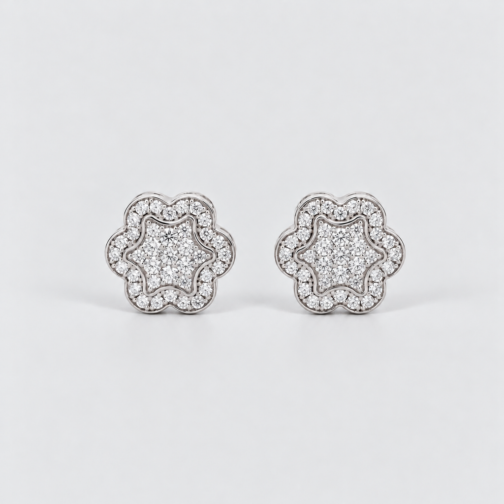 A pair of silver-toned flower-shaped stud earrings paved with clear cubic zirconia stones, displayed on a clean light gray background.