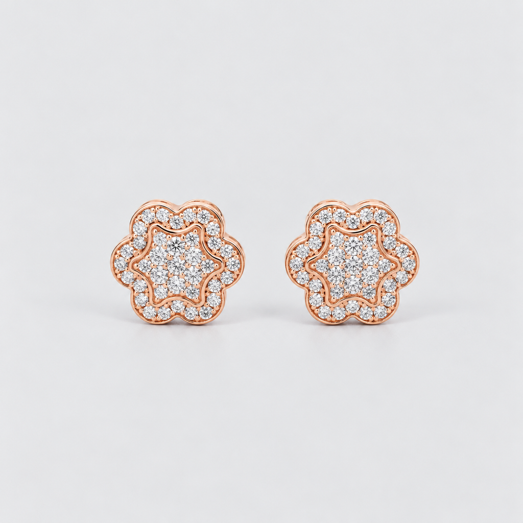 A pair of rose gold stud earrings with a double halo design, featuring pavé-set clear stones. The earrings are shown on a clean, light gray background.