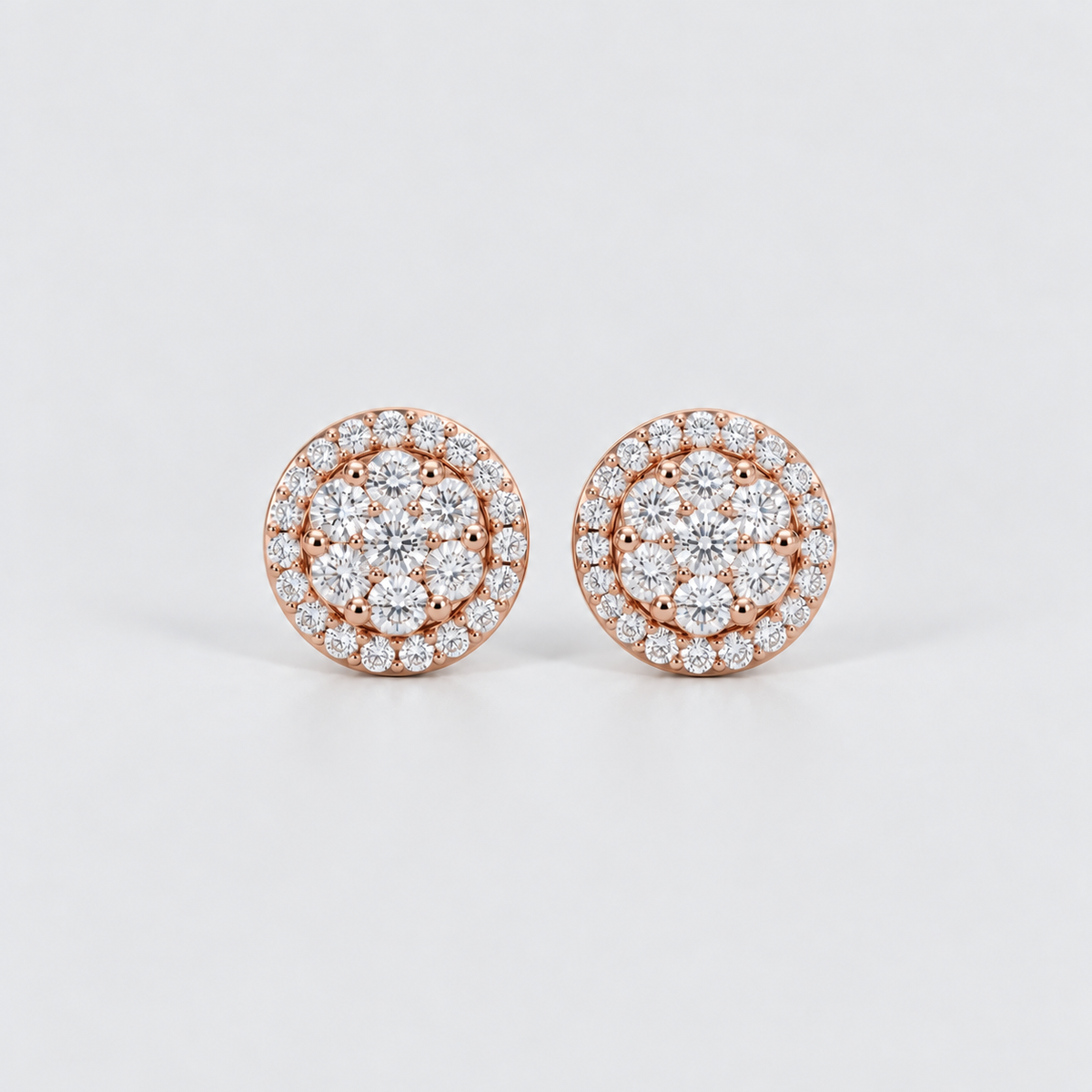 A pair of round rose gold stud earrings set with multiple clear gemstones in a halo design, photographed on a clean light gray background.
