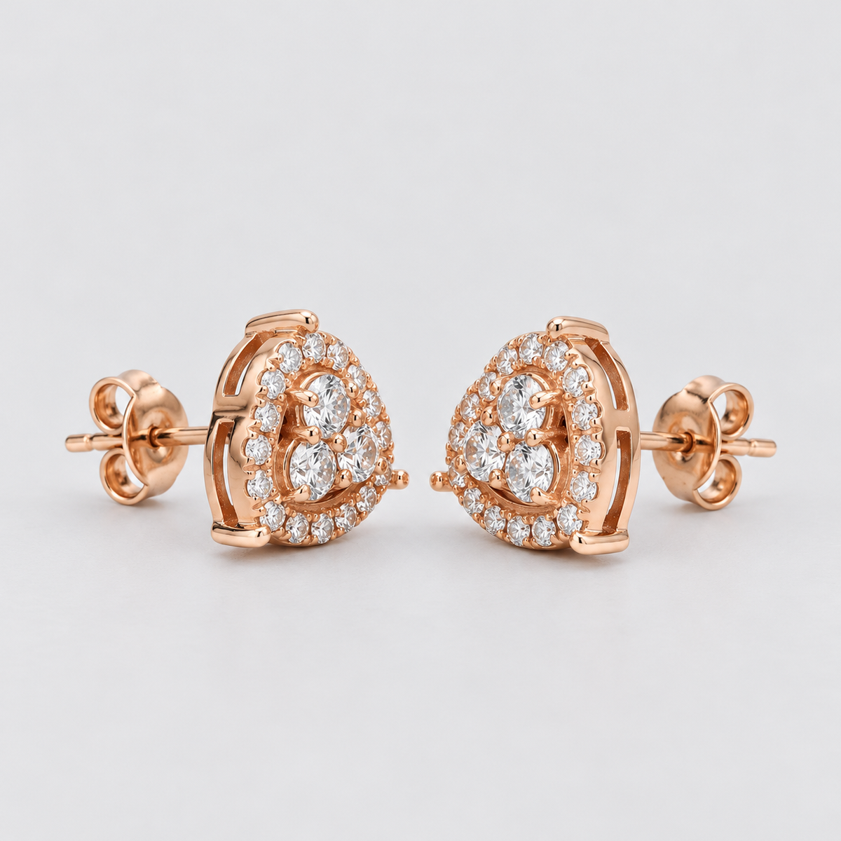 A pair of rose gold stud earrings with heart-shaped pavé diamond settings, shown on a light gray background.