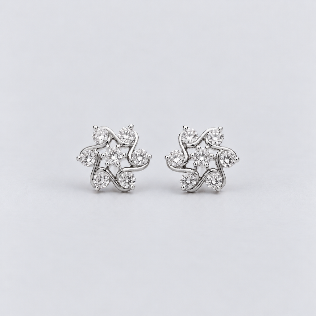 A pair of silver-toned stud earrings with a floral, leaf-like cluster design set with clear round gemstones, displayed on a light gray background.