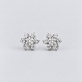 A pair of silver-toned stud earrings with a floral, leaf-like cluster design set with clear round gemstones, displayed on a light gray background.