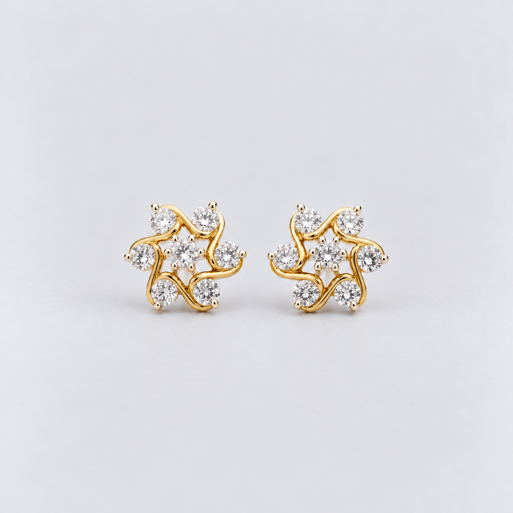 A pair of gold stud earrings featuring a swirling vine design set with clear round-cut gemstones, photographed on a clean light gray background.