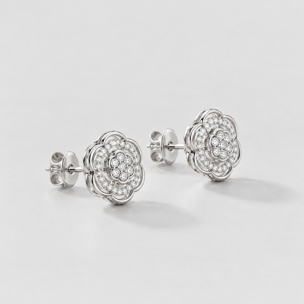 A pair of silver-toned flower-shaped stud earrings with pavé-set clear stones, displayed on a clean light gray background.