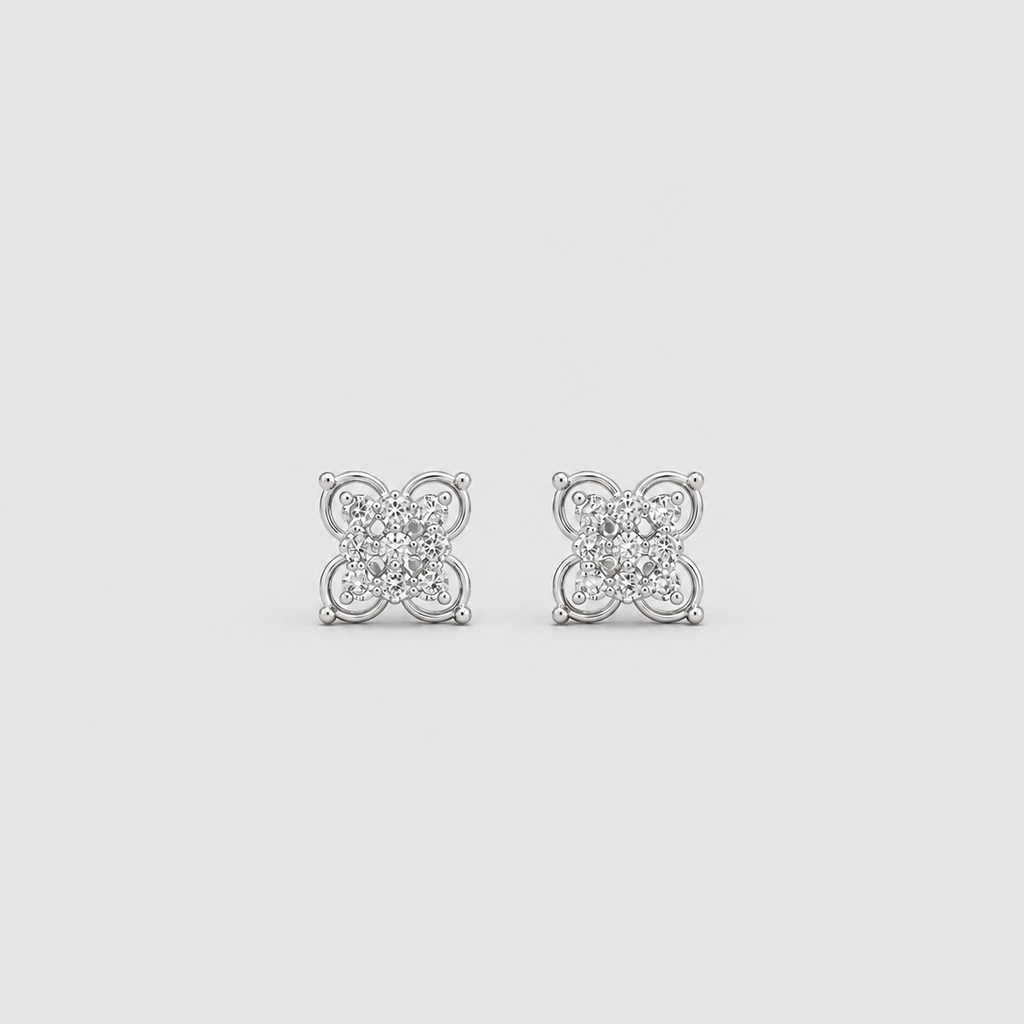 A pair of silver-toned square stud earrings with a floral or clover-like design set with small clear stones, shown on a light gray background.
