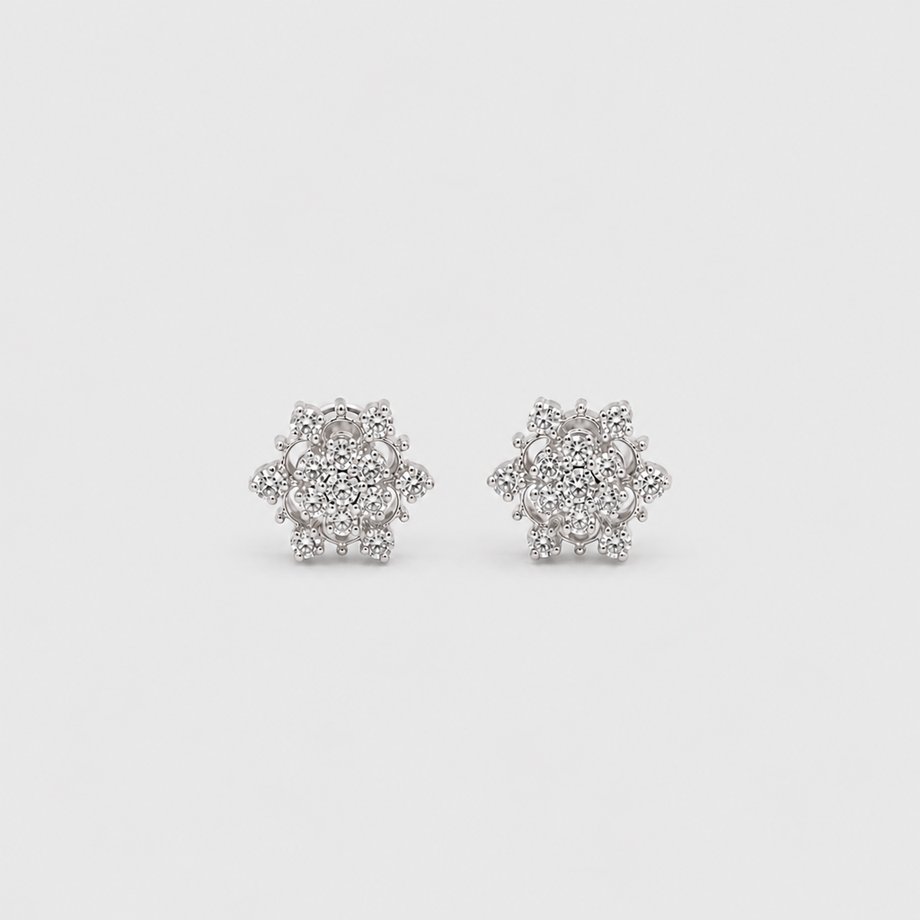 A pair of snowflake-shaped stud earrings made of silver-toned metal and clear stones, displayed on a light gray background.