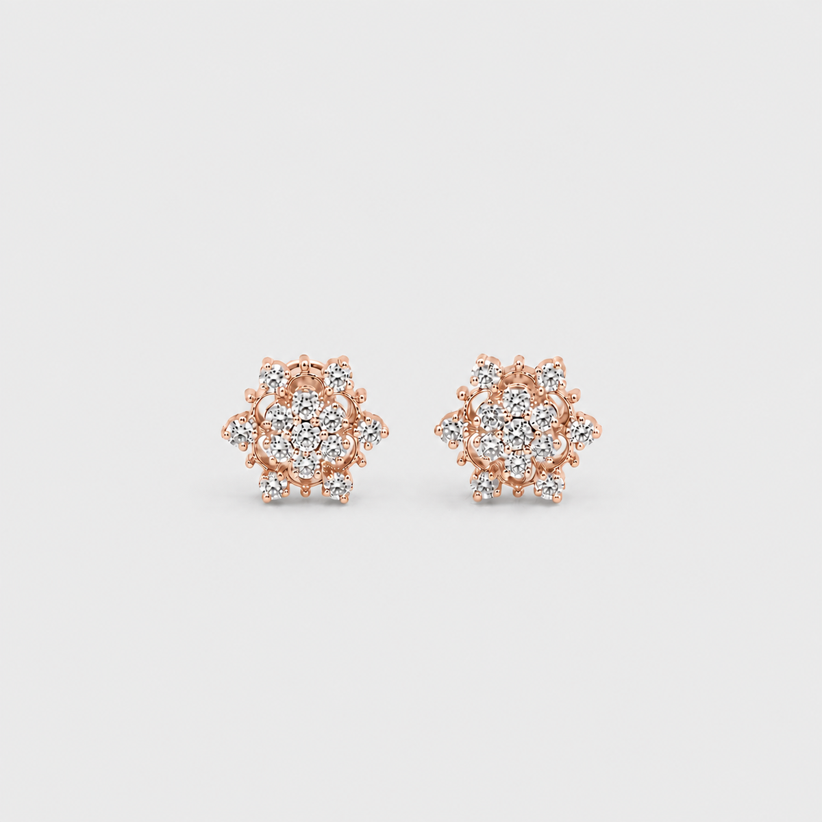 A pair of rose gold stud earrings with clear gemstones, arranged symmetrically on a light gray background.