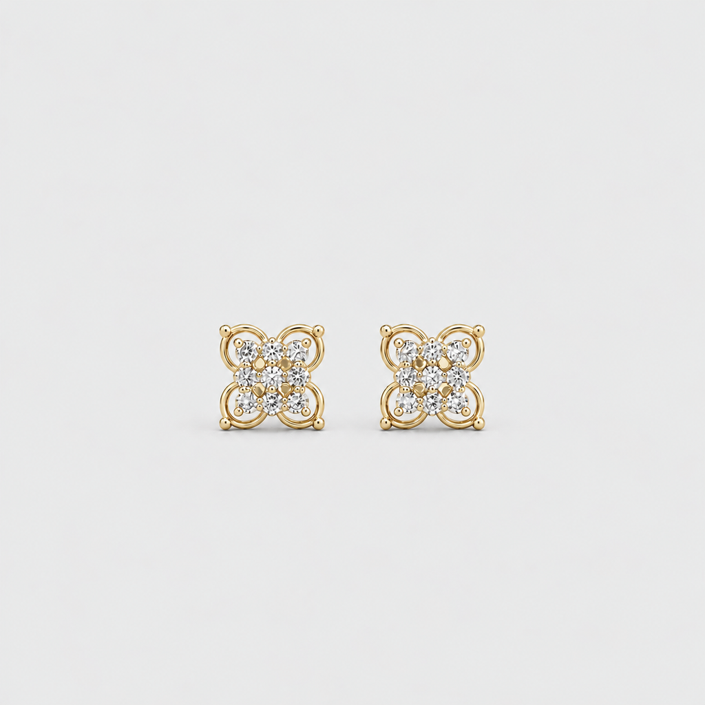 A pair of gold stud earrings with a four-petal flower design set with small clear gemstones, shown on a light gray background.