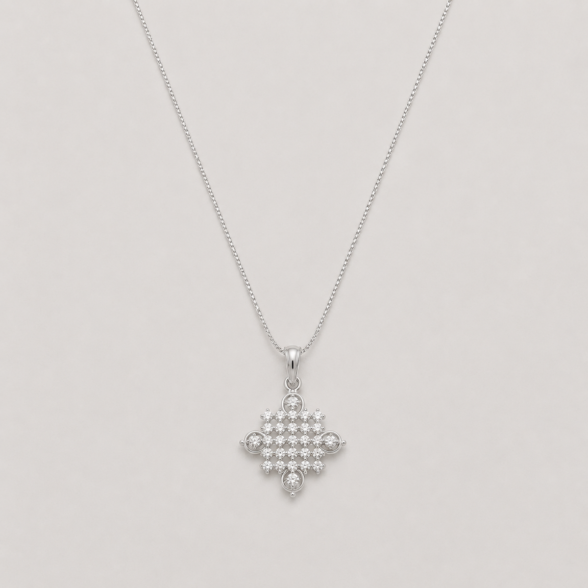 A silver cross pendant necklace adorned with small clear gemstones, suspended from a delicate silver chain against a light gray background.