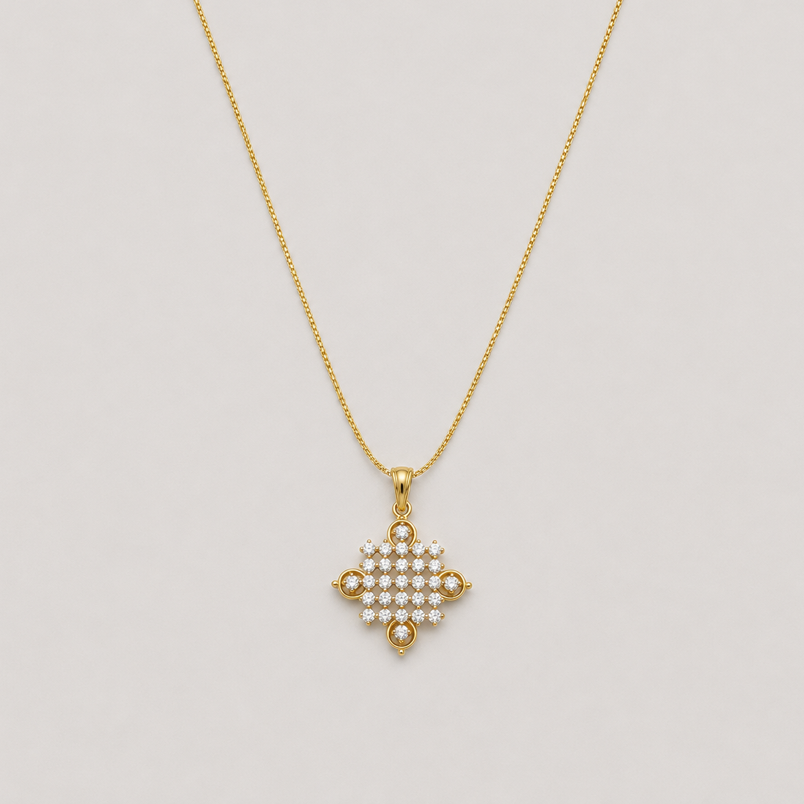A gold chain necklace with a delicate cross-shaped pendant adorned with small white stones, set against a light gray background.