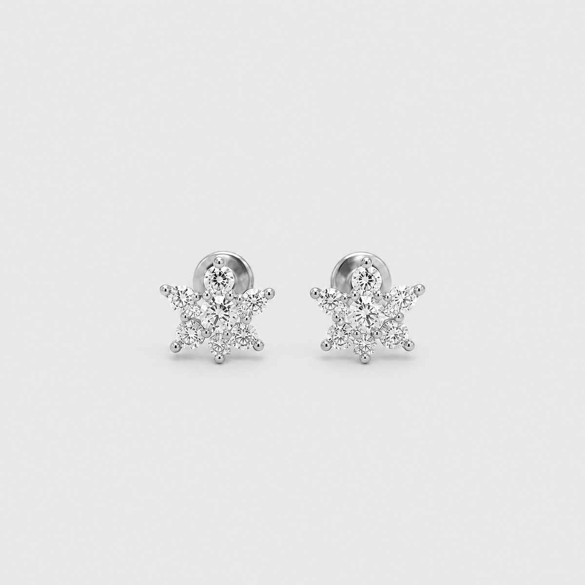 A pair of silver snowflake stud earrings set with clear cubic zirconia stones, displayed on a light gray background.