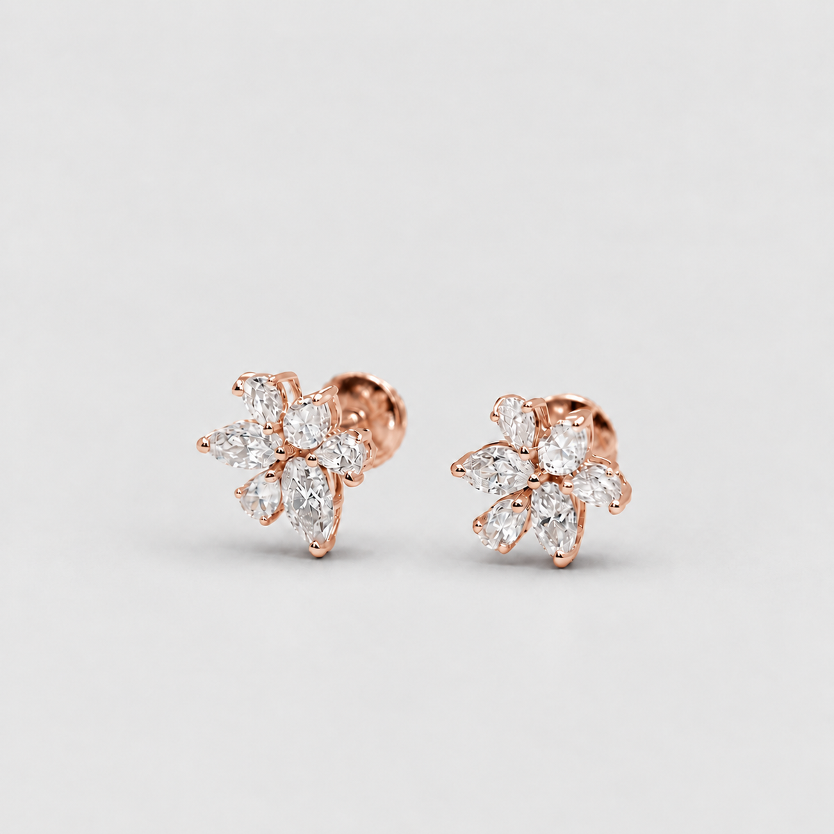 A pair of rose gold flower-shaped stud earrings set with marquise-cut clear gemstones, displayed on a clean light gray background.
