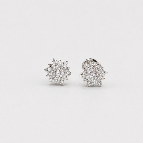 A pair of silver-toned starburst stud earrings with clear pavé gemstones, shown on a clean light gray background.