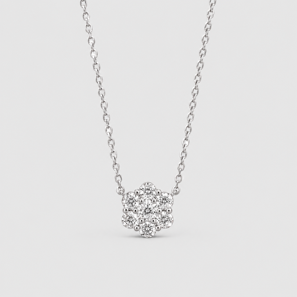 A silver-toned necklace with a small flower-shaped cluster of clear stones on a delicate chain, shown against a light gray background.